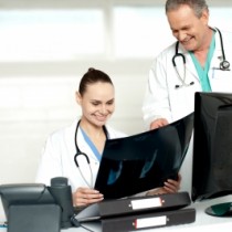 Female and Male doctor analysing xray in front of computer and desk