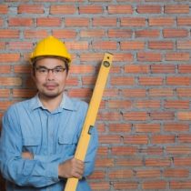Manufacturing man in shirt against wall with yellow hat and ruler
